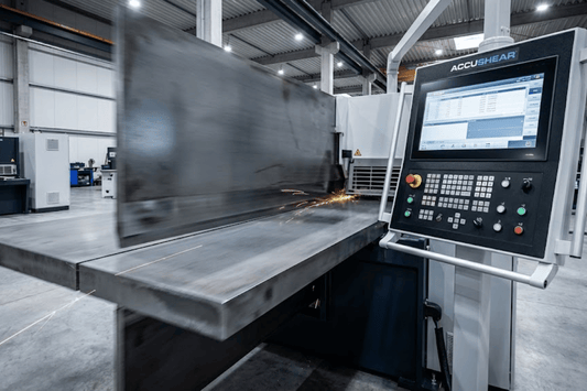 CNC metal shearing machine cutting a large steel plate in a bright factory, control panel displaying cutting program and sparks