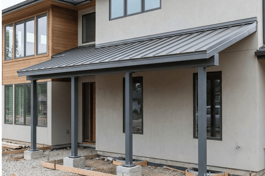 Modern two-story house front with covered porch, metal roof, three steel columns on concrete footings and unfinished landscaping